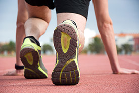 Photo of a runner crouching at the starting line of a track