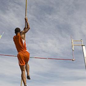 Low angle view of a male athlete performing a pole vault against the sky